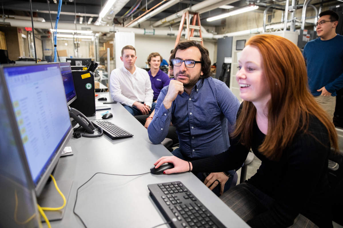 student smiles at console with professor by her side